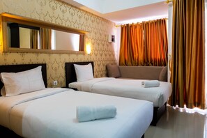 Two single beds with white duvets and towels, a large mirror, and a window with curtains.