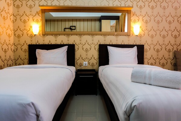 Two single beds with white linens, flanked by black nightstands and a large mirror.