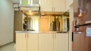 A modern kitchen with light wood cabinets, stainless steel appliances, and a built-in range hood. - Prime Location Studio Apartment at Elpis Residence near Ancol (Jakarta)