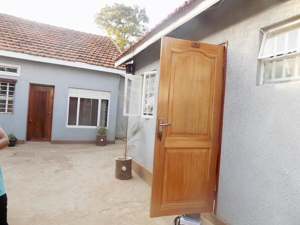 A residential building with a wooden door, a window, and a potted plant.