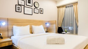 A neatly made bed with white linens, a wooden headboard, bedside tables with lamps, and framed pictures on the wall.