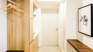 A hallway with wooden cabinets, a wooden bench, a door, and a framed picture on the wall.