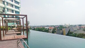 A wooden deck with a pool extending into a cityscape.