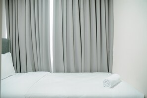 Une chambre d’hôtel avec un lit bien fait, un oreiller et une serviette enroulée posée sur le lit.