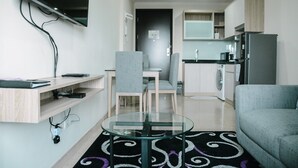 Uma sala de estar moderna com uma mesa de centro de vidro, sofá cinza e TV fixada na parede.
