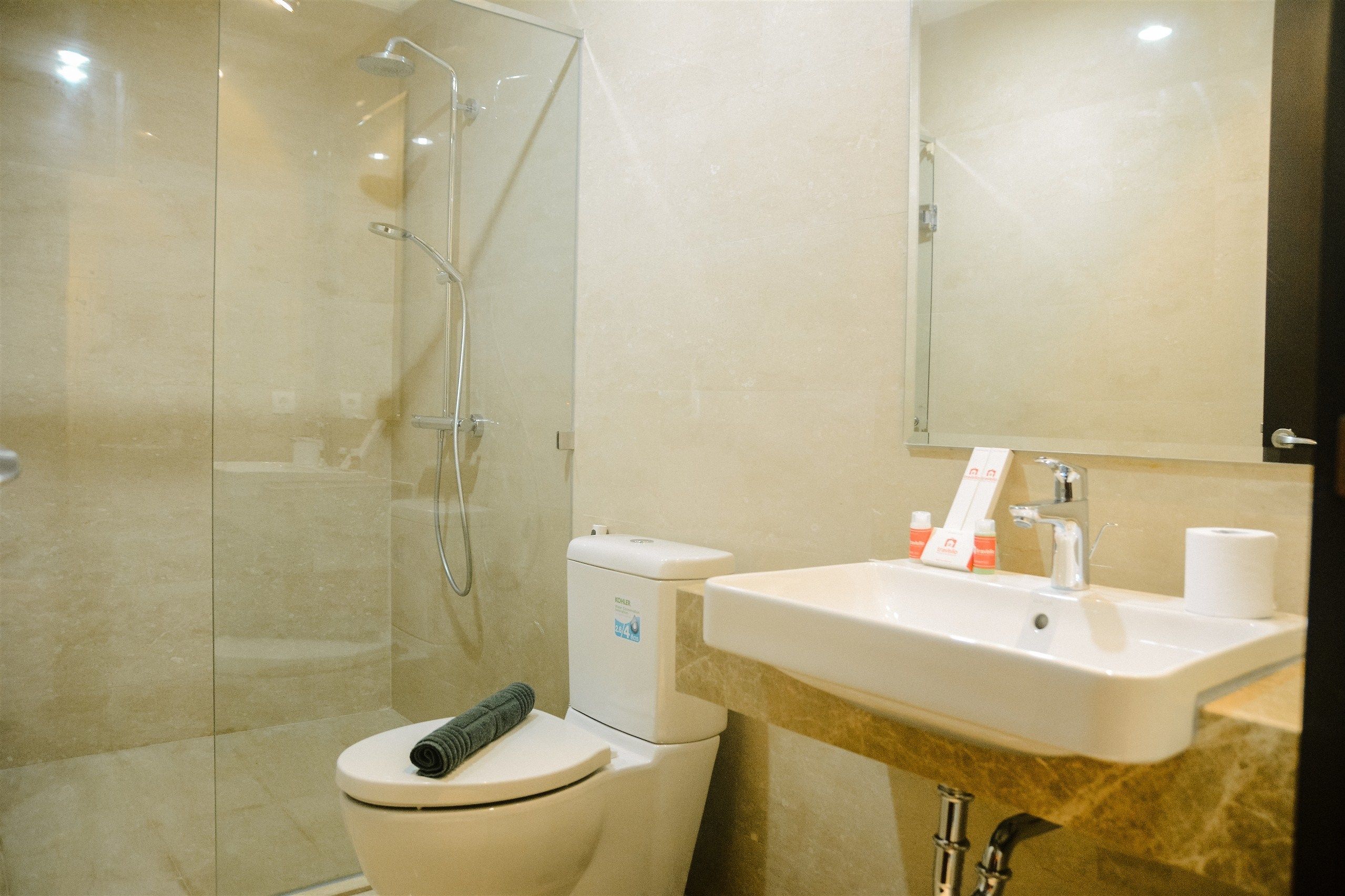 Un baño moderno con ducha de vidrio, inodoro blanco y lavamanos con encimera de mármol.