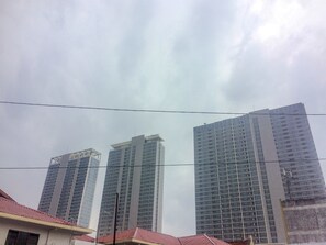 Trois immeubles de grande hauteur se dressent sous un ciel nuageux.