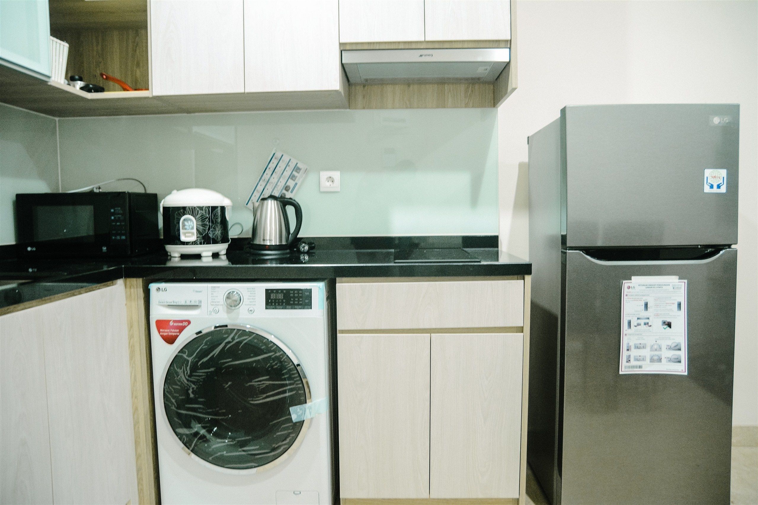 Eine kompakte Küche mit Waschmaschine, Mikrowelle, Kaffeemaschine und Kühlschrank.