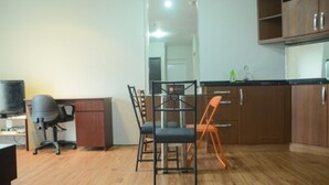 Une cuisine compacte avec des meubles en bois, une table à manger avec quatre chaises et un téléviseur posé sur un bureau.