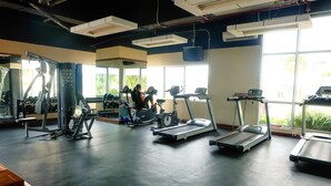 Une salle de sport équipée de tapis de course, de vélos d’exercice et d’appareils de musculation.