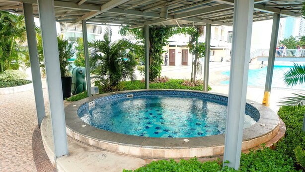 Une piscine couverte, bordée de carreaux, entourée de verdure et dotée d’une allée également carrelée.