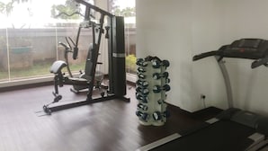 A gym with a treadmill, weight machine, and dumbbells. - Simply Homey Studio Room at GP Plaza Apartment (Jakarta)