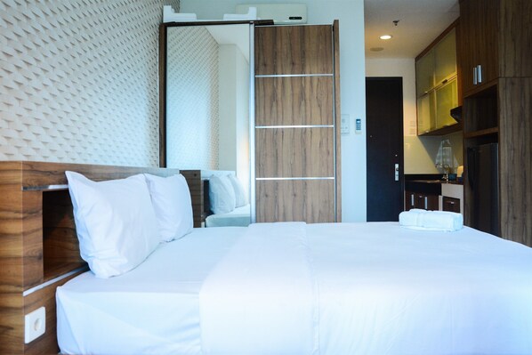 Een moderne hotelkamer met een groot bed, een houten hoofdbord en een schuifdeurkast.