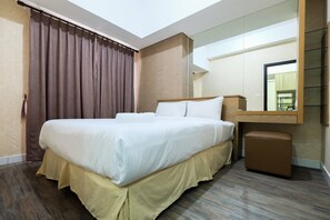 Ein Hotelzimmer mit einem großen Bett, einem Nachttisch, einem Spiegel und einem kleinen Hocker.