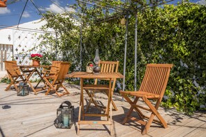 Relax in this serene outdoor seating area with a table and four chairs, surrounded by lush greenery and a pergola.