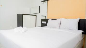 Una habitación de hotel con una cama bien hecha, un armario y un espejo en la pared.