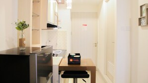 Una cocina compacta con refrigerador, lavamanos y encimera. Hay una pequeña mesa con una caja etiquetada 'travelio'.