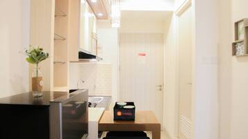 A compact kitchen with a refrigerator, a sink, and a countertop. There is a small table with a box labeled 'travelio' on it.