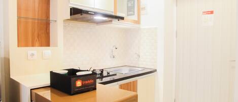 A compact kitchen with a sink, a microwave, and a travel bag on the counter.