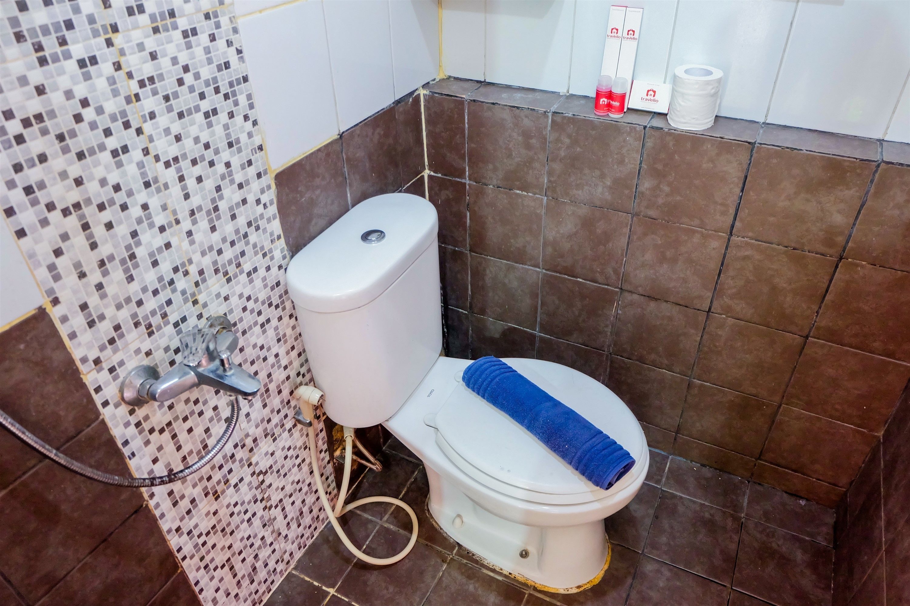Une salle de bain avec des toilettes, une douche et des murs carrelés.