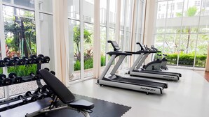 A gym with treadmills, dumbbells, and a bench. - Simply Homey Studio Casa De Parco Apartment (Pagedangan)