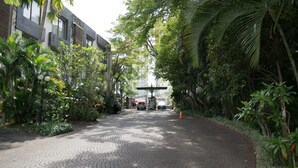 Un chemin pavé, tracé selon un motif circulaire, bordé d’une végétation luxuriante et d’un bâtiment à l’architecture moderne.