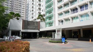 L’entrée d’un hôtel au design moderne, un espace paysager aménagé et un panneau indiquant l’emplacement du parking.