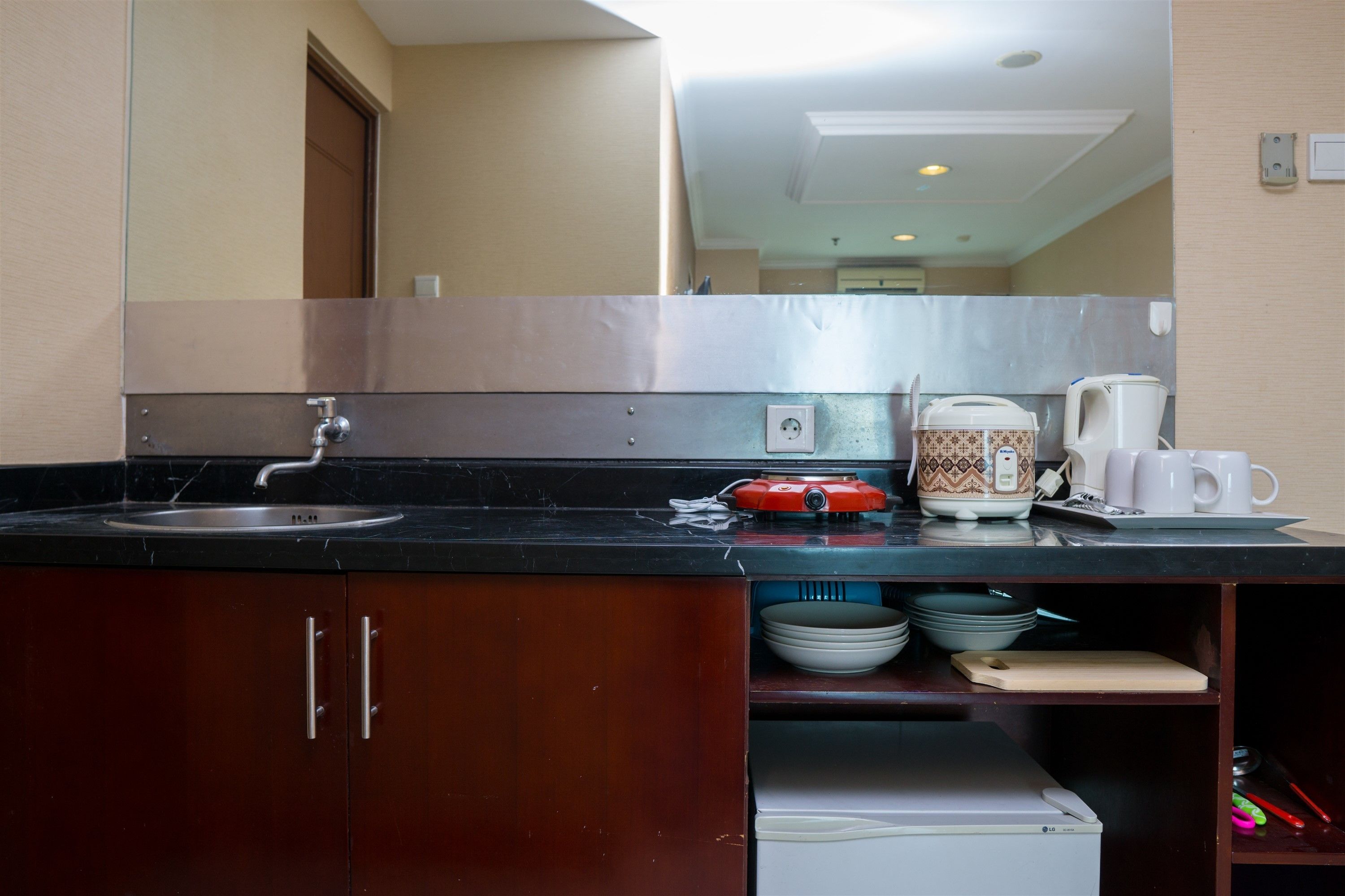 A compact kitchen with a stainless steel sink, a coffee maker, and a microwave.