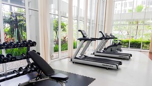A gym with treadmills, dumbbells, and a bench. - Nice & Comfy Studio Apartment Casa De Parco (Pagedangan)