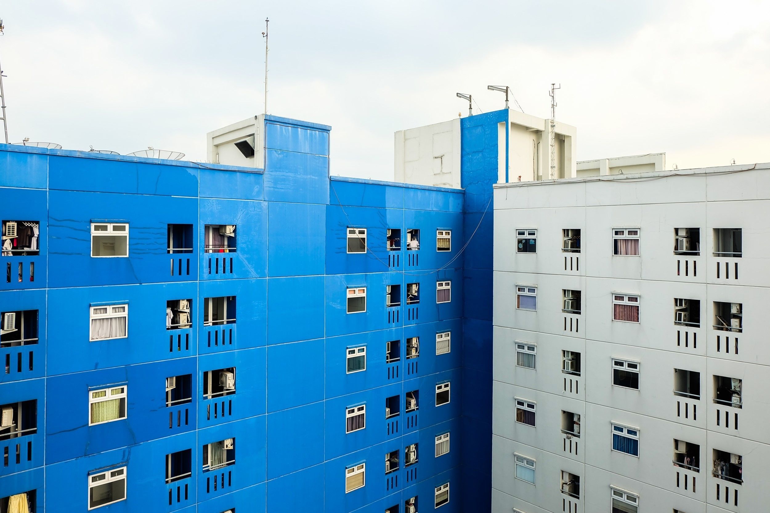 Un edificio de varios pisos con fachada azul y ventanas blancas.