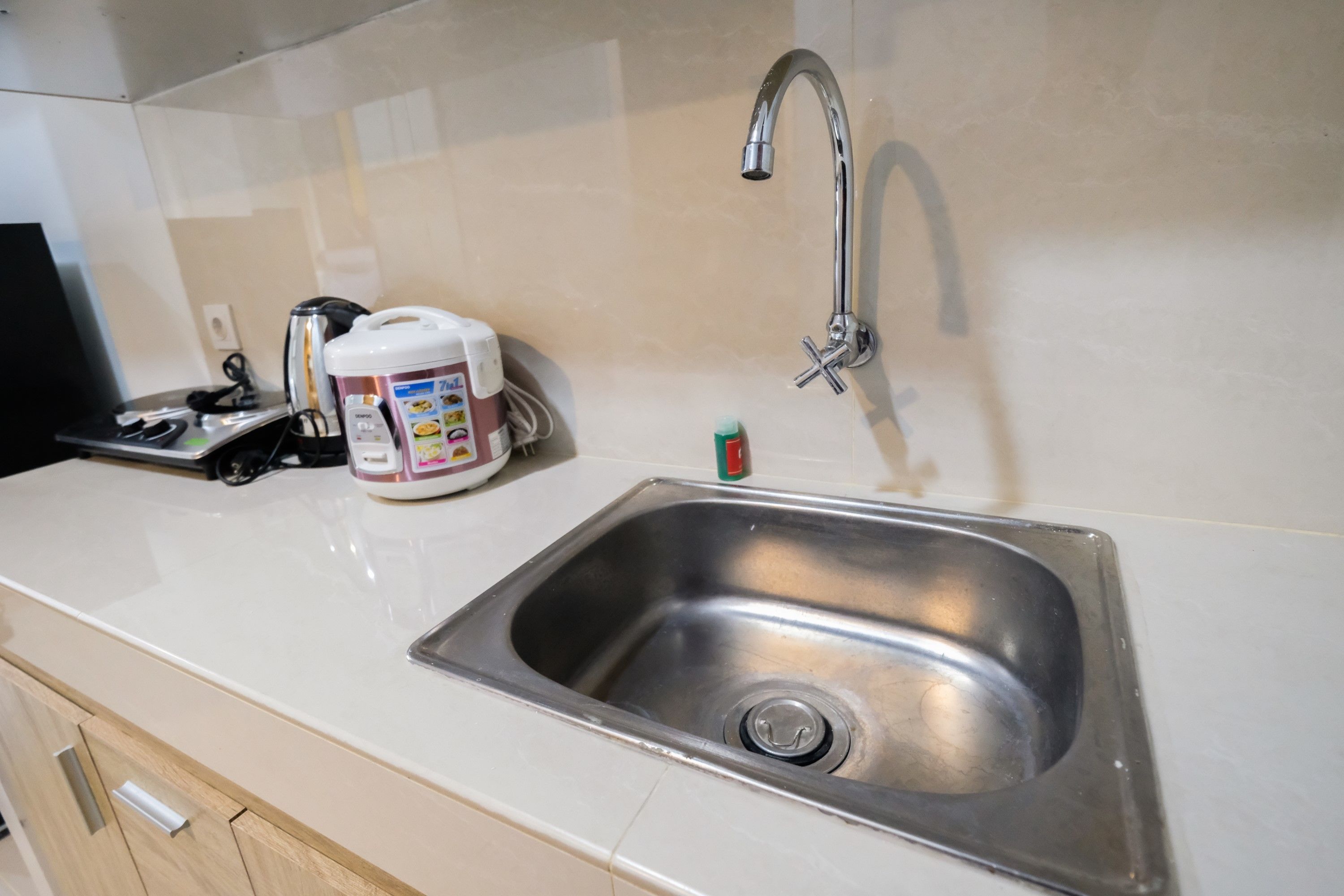 A kitchen with a stainless steel sink, a coffee maker, and a small bottle of dish soap.