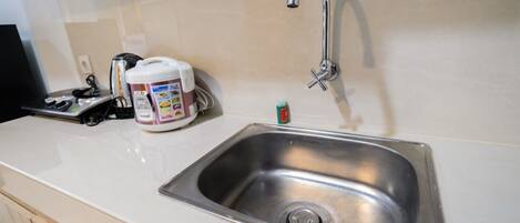 A kitchen with a stainless steel sink, a coffee maker, and a small bottle of dish soap.
