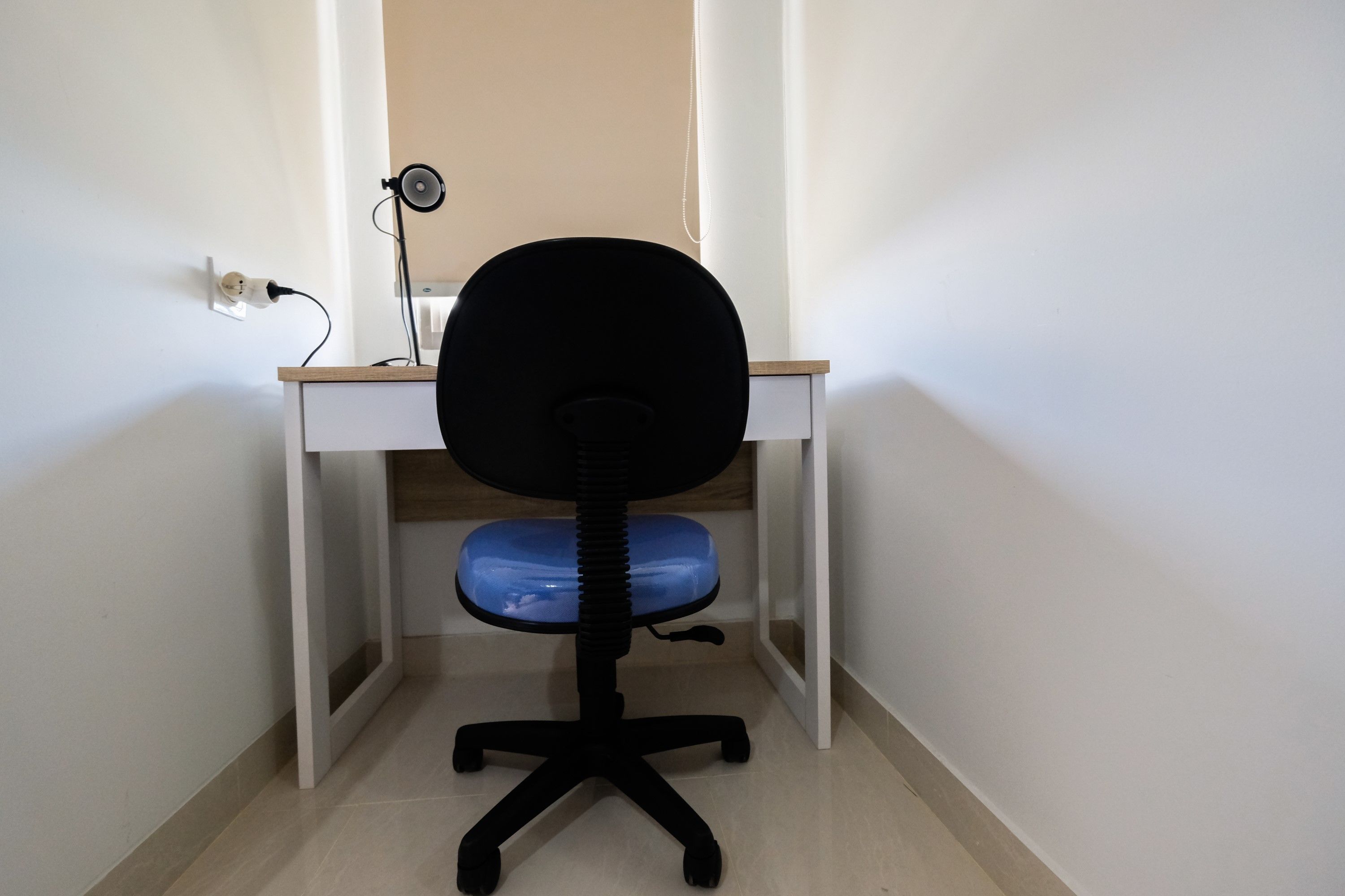 A corner office with a desk, chair, and a lamp.