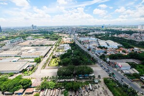 An aerial view of a cityscape with a mix of industrial and residential buildings, a central road, and surrounding greenery. - Exclusive Studio Apartment Springwood Residence (Tangerang)