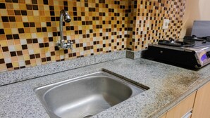 A kitchen with a granite countertop, a stainless steel sink, and a tiled backsplash. - Minimalist Studio Room Great Western Apartment (Tangerang)