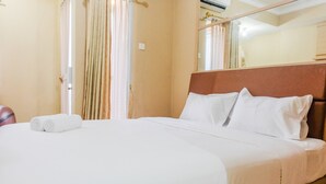 A hotel room with a large bed, white linens, a wooden headboard, and a mirror on the wall. - Minimalist Studio Room Great Western Apartment (Tangerang)