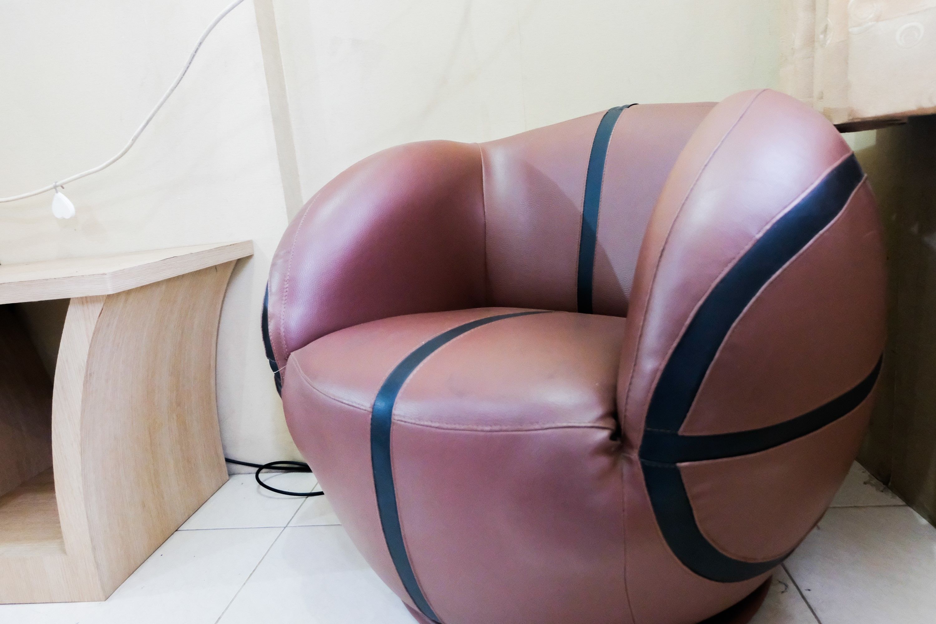 A corner room with a unique curved chair and a wooden cabinet.