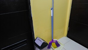 A corner of a room with a mop and bucket, a broom, and a trash bin. - Minimalist Studio Room Great Western Apartment (Tangerang)