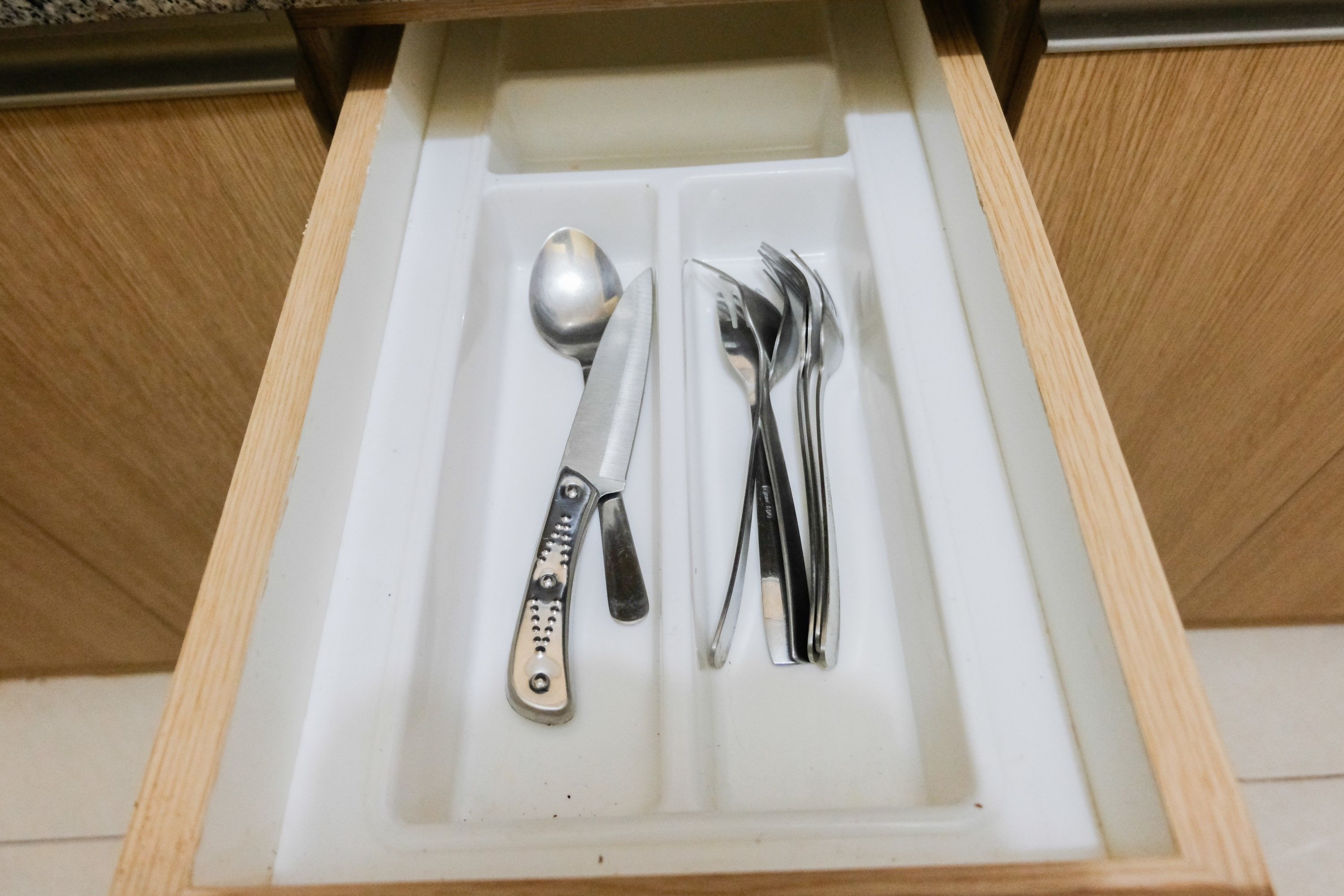 A drawer with a knife, spoon, and forks.