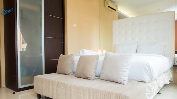 Une chambre d’hôtel avec un grand lit, un canapé, une porte coulissante et un climatiseur fixé au mur.