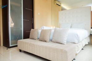 Une chambre d’hôtel avec un grand lit, un canapé, une porte coulissante et un climatiseur fixé au mur.
