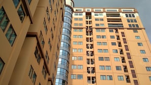 Un immeuble de grande hauteur, doté de nombreux étages, dont la façade est composée d’un mélange de verre et de murs de couleur beige.