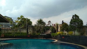Une piscine à bord incurvé, entourée d’un mur de pierre et de verdure.