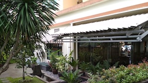 Une cour avec un bassin à carpes koï, des plantes en pot et une structure en forme de pergola.