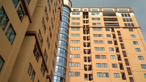 Un immeuble de grande hauteur, doté de nombreux étages, dont la façade est composée d’un mélange de verre et de murs de couleur beige.