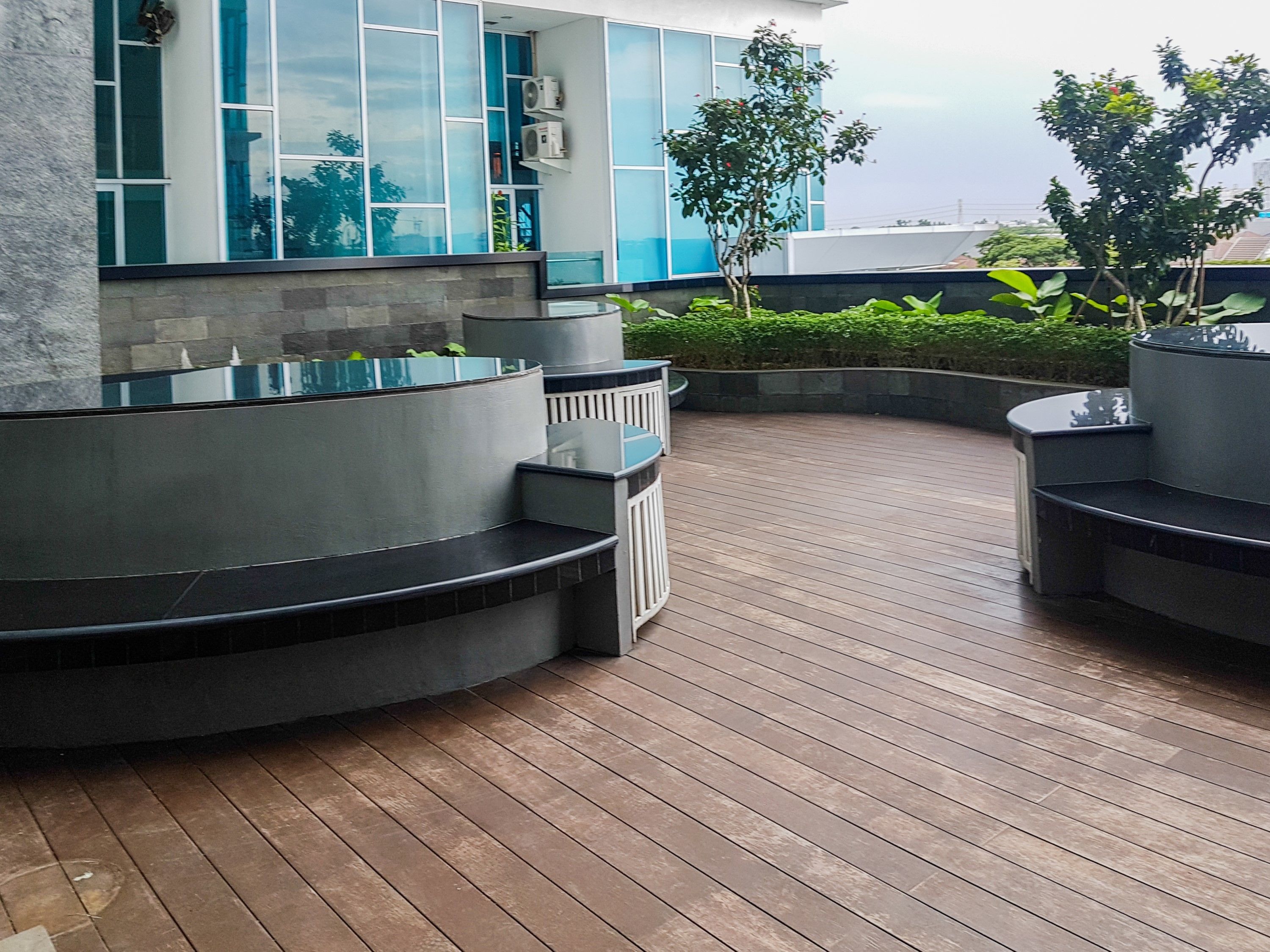 A modern outdoor seating area with curved benches and a wooden deck.