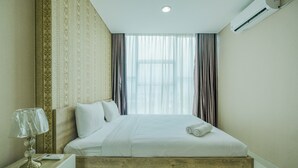 Ein Hotelzimmer mit einem Bettgestell aus Holz, einem Nachttisch mit Lampe und einem großen Fenster mit Vorhängen.