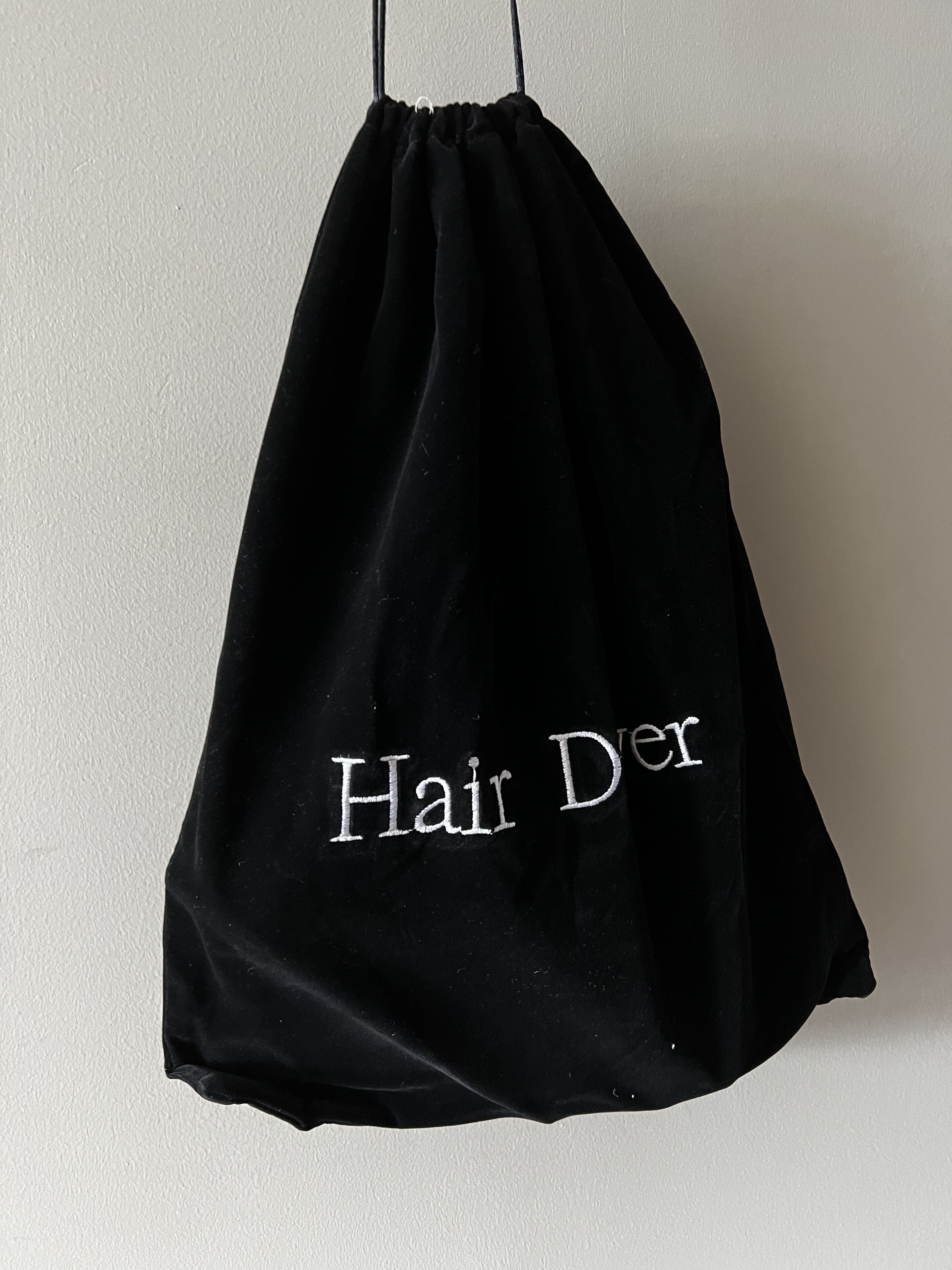 A black drawstring bag with the text "Hair Der" visible on it.