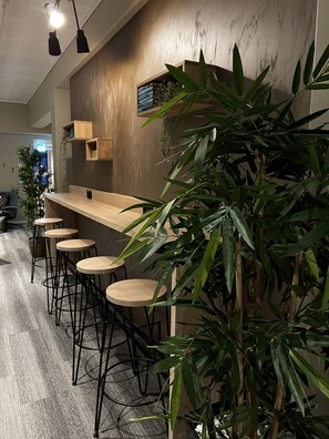 A modern bar area with wooden stools, a counter, and potted plants. - Frich´s Ekspress Hotel Åndalsnes (Rauma)