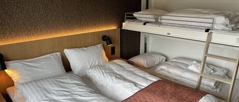 Een hotelkamer met een stapelbed, een enkel bed en een gewatteerde spreidek.